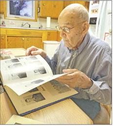 Raymond Kolbo takes a walk down memory lane as he sits at his kitchen table leafing through a book chronicling his life in the Army. (Courier photo by Ellen Mortensen)