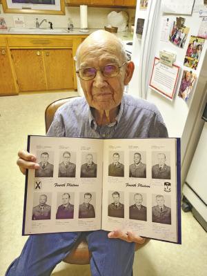 Korean War-era veteran Raymond Kolbo holds up the page in his book with his photo from 1952. He is the soldier in the bottom row, second from left. (Courier photo by Ellen Mortensen)