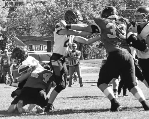 Photos courtesy Loleta Connell #24 Junior Lance Wooters takes down the Warrior ball carrier while #33 Junior Joey Sallach fights his way through two more on the play.