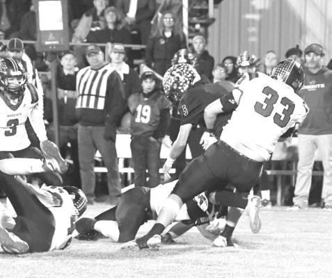 Above: The Bobcat fans and student section were out in force for the Nov. 10 game in Dunning with the theme 'white lies'. Right: Joey Sallach (#33) stops Knight ballcarrier Kyle Cox in his tracks for a loss on the play. (Courier photos by Loleta Connell)