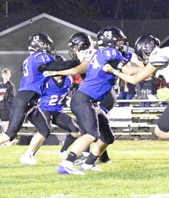 ABOVE: Jamie Tickle, Kyle Bloomer, Ethan Furne, Conner Paulsen, Dylan Pandorf and AJ Starr get ready to make a play in the rain at Friday night's game in Callaway. LEFT: Harper Johnson (#13) and Crew Witthuhn (#44) hold off a couple of Acadia-Loup City players during the final regular season game for the Bobcats on Oct. 18. (Courier photos by Jessica Tickle)