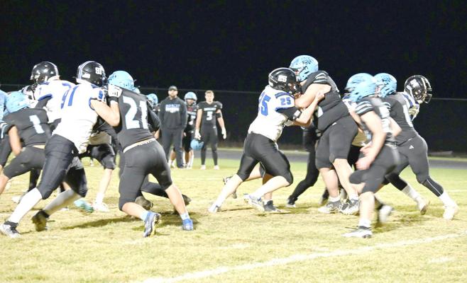 ABOVE: Patrick Eggleston (#7), Caleb Furrow (#91), and Malachwi Neth (#25) work hard on the line to hold off Summerland. LEFT: Devyn Denney (#99) tackles a Summerland Bobcat.