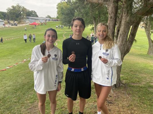 A group of three athletes hold their medals and smile at the camera.