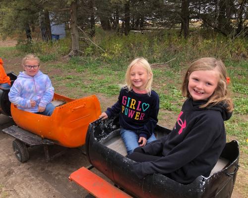 Three students smile for the camera as they ride a mini sized train