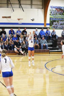 Ava Pandorf is midjump as she sets a volleyball