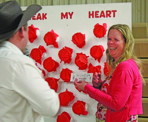 Mary Ross laughs as she opens the punch cup she won with the high bid to reveal the prize inside to auctioneer Jake Judge. The Break My Heart punch cup game was a popular new addition to the live auction at the Callaway Community Foundation Fund Gala held Saturday, Feb. 14, at the Callaway Community Center. (Courier photo by Ellen Mortensen)