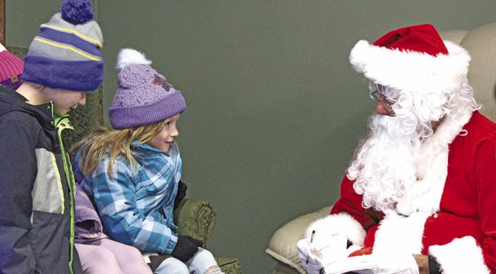 Due to the chilly temperatures visits with Santa were moved inside the library. Here Santa visits with a couple of local children about their Christmas lists this year.