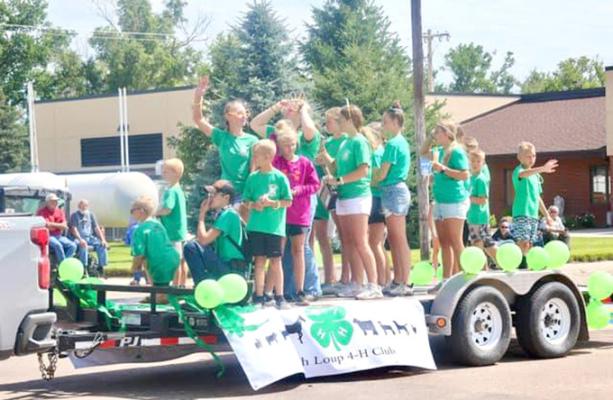 TOP LEFT: This parade entry was having fun hosing down some of the crowd during the parade on Saturday, June 29. ABOVE: Members of the South Loup 4-H Club wave to the crowd as their float comes down the street.