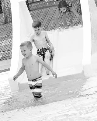 ABOVE LEFT: Hank and Caroline Svoboda were the first ones in the new pool on Saturday, after their parents Dr. Tiff and Bill Svoboda purchased that prize during the Chamber Gala. The family also received a gift bag filled with pool goodies. ABOVE RIGHT: The kids were eager to try out the new water slide, which was a popular feature throughout opening day. (Photos courtesy Rhonda McFate)
