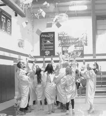 ABOVE: The class of 2022 throw their caps in the air following the commencement ceremony at Callaway High School on Sunday. LEFT: Mya Weverka hugs junior Taylor Ross during the flower ceremony on Sunday during the Class of 2022 commencement at Callaway Public Schools. (Courier photos by Amanda Koubek-Wehnes)