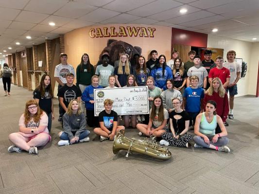 A group of students sits around a tuba and oversized check 