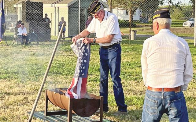 Callaway American Legion Post 50 hosted a flag retirement ceremony on Monday evening, July 4. Pictured are Dave Chesley, placing a flag into the burn receptacle with Dale Estergard looking on. Photo courtesy Susan Phelps