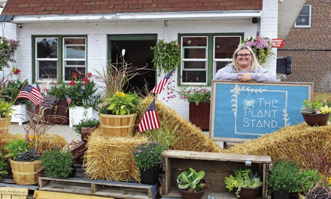 Jessie Bloomer standing by her business sign, labelled 'The Plant Stand'