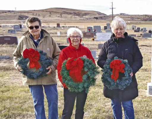 Callaway American Legion Auxiliary members, from left, Jo Chesley, Mary Ann Boldt, and Joyce Kolbo help place Christmas wreaths on the graves of veterans at Rose Hill Cemetery. This is the fifth year of the project. (Courier file photo by Ellen Mortensen)