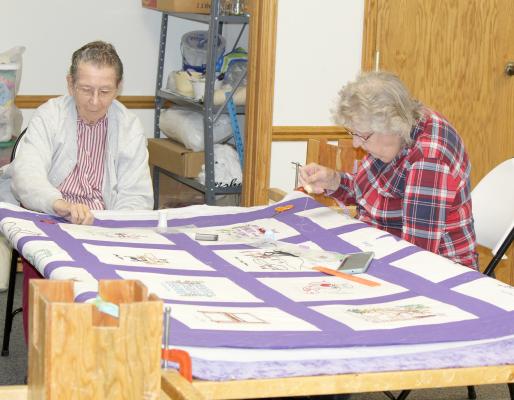 Shirley Pierce and LaVonne Hickenbottom work on a quilt that when finished will be gifted to the former pastor of Morning Star Church. Each block was embroidered by someone in the family that block represents. (Courier photo by Ellen Mortensen)