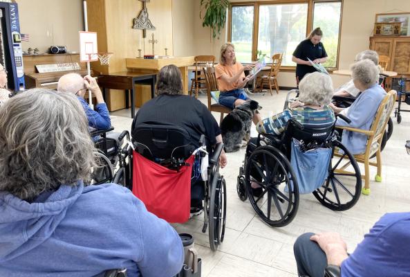 Oconto author Yvette Mannon read her latest children’s book to residents of Callaway Good Life Center last week. She was joined by Cookie the blue heeler, the main character in all of Mannon’s books. The second book has a connection to the nursing home that surprised many of the residents. (Photo courtesy Tammy Coons-CGLC))