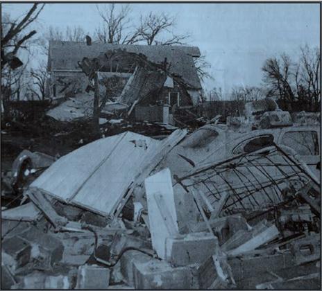 Pictured are tossed piles of debris with the severely damaged community hall in the background. (Courier file photo)