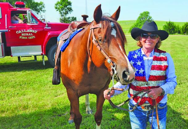 Kaye Myers of Oconto prepares to ride her horse, Dollie, in the Oconto Fun Day Parade in support of US troops.
