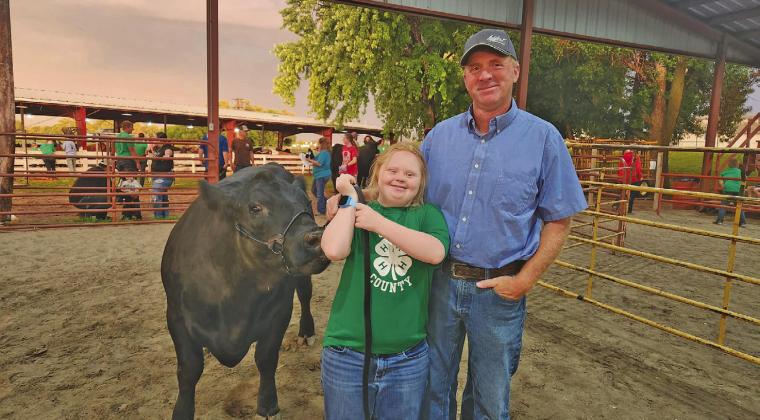 Catherine “Katie” Phelps and her father, Jim, hold onto Katie’s 1,140 lb. blue ribbon steer as they wait in line to enter the auction ring at the Custer County Fair last Thursday.